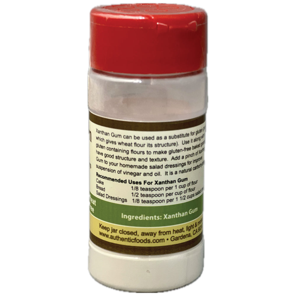 A plastic bottle of Xanthan Gum with a red cap and a white label showing usage instructions and ingredients, isolated on a white background.