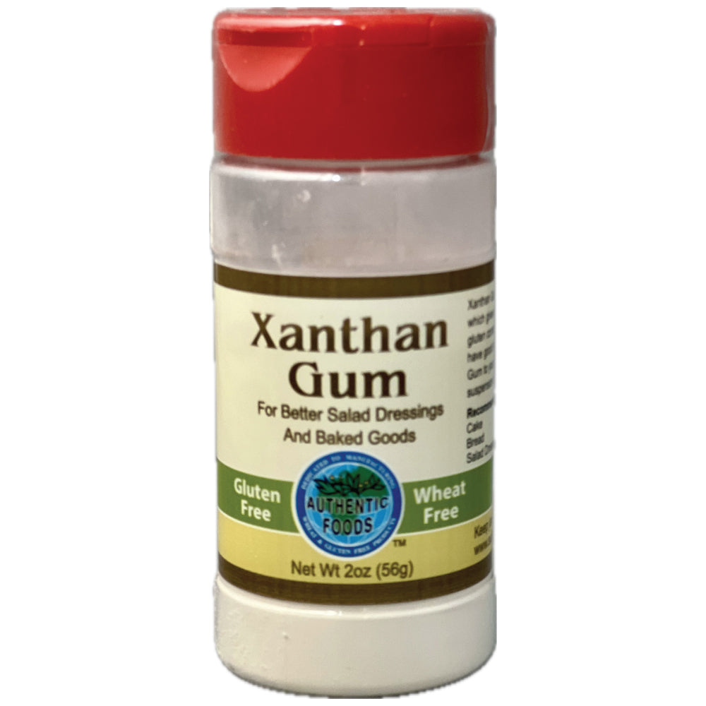 A 2 oz plastic bottle of Xanthan Gum, a gluten and wheat-free authentic food ingredient, featuring a red cap and a cream-colored label with green and brown accents.