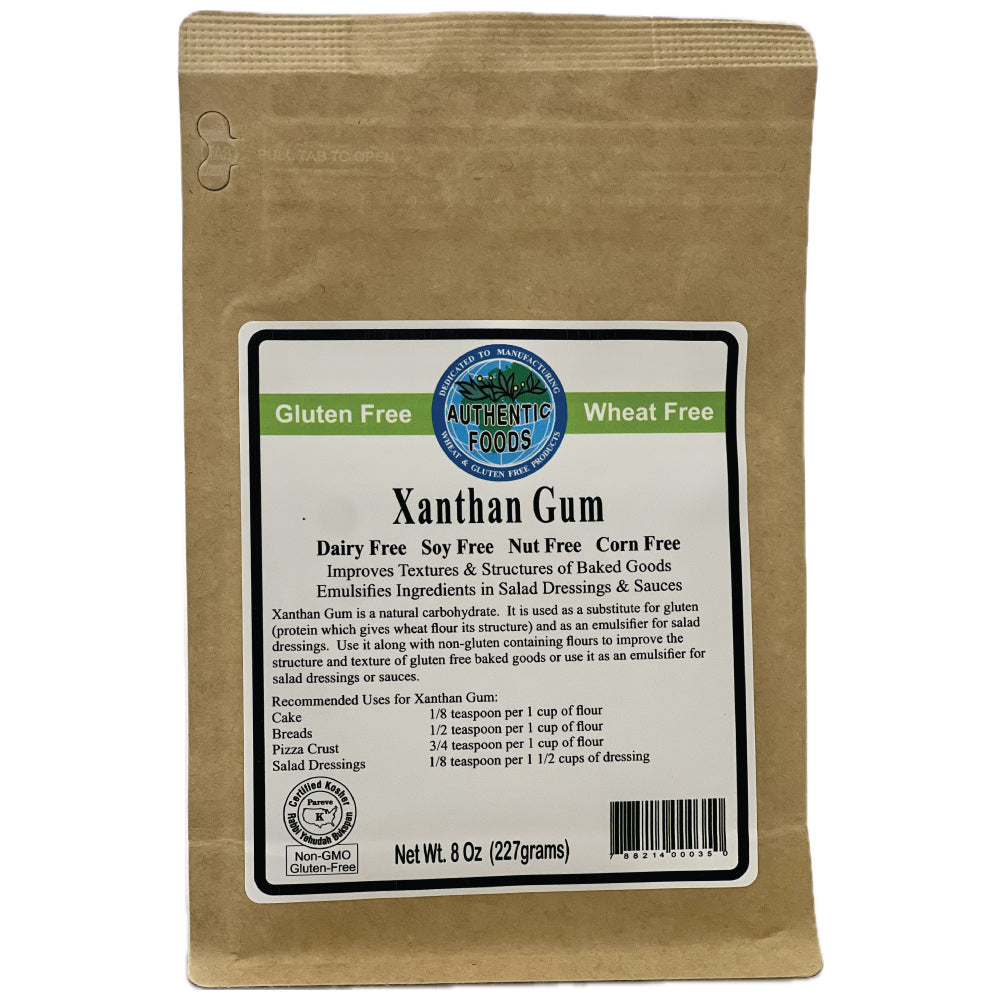 An 8 oz kraft paper stand-up pouch of Authentic Foods Xanthan Gum, featuring a white and green label with product details and a barcode.